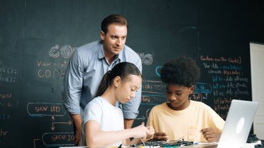 Kafkas öğretmeni elektrikli aletten bahsederken öğrenci de elektronik ekipmanlarla robot modelini tamir ediyor. Çeşitli akademik çocuklar ana kurul yapısını öğreniyor. Öğretim.