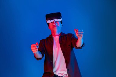 VR kullanan zeki bir oyuncu araba yarışlarında araba sürerken yeni dünyaya dönüyor mavi neon ışıklı duvar bağlantılı fütüristik teknoloji sanal gerçeklik meta 'sını izole ediyor. Entrika.