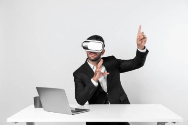 Bilgisayarla masada otururken ve VR gözlüğü takarken veri analizine bakan yetenekli bir iş adamı. Proje yöneticisi sanal gerçeklik sistemini kullanarak ya da metaevrende bağlantı kurarak çalışıyor. Sapma.