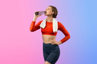 Vücut uzunluğunun tamamı atletik ve sportif genç bir kadını havluyla ve içme suyuyla izole edilmiş arka planda egzersiz yaparken çekilir. Sağlıklı aktif ve vücut bakımı yaşam tarzı.