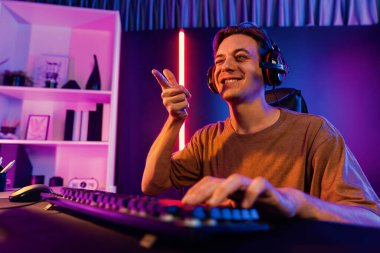 Kazanmak için çevrimiçi oyun oynayan akıllı flama makinesinin sunucu kanalı, neon ışıklı odada seçilen takım yarışması için izleyicilerle birlikte canlı yayında canlı yayında kulaklık takıyor. Bireysel.