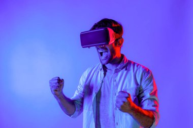 Sanal dünyada spor müsabakalarını izleyen mutlu adam neon ışıklı arka planda VR kulaklık takıyor. Yakışıklı genç, gelecekteki yenilik teknolojisine gözlük kullanarak giriyor. Sapma.