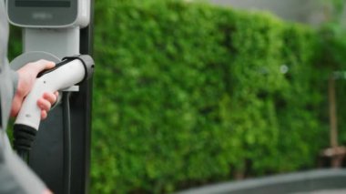 Yazın yeşil sürdürülebilir şehir bahçesinde çalışan genç EV elektrikli araba yeşil sürdürülebilir şehirde yeniden şarj edilebilir elektrikli araç iç organları için alışveriş yapan genç bir çiftin yaşam tarzını gösteriyor.