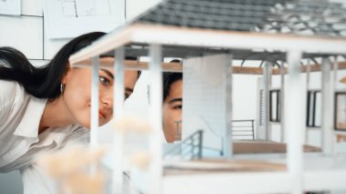 Ev modeli yapısını ölçmek için birlikte çalışan kooperatif mühendisi kapatın. Genç ve güzel mimar ev modelini ölçerken erkek mühendis performansını destekliyor. Tertemiz..