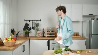 Mutlu baba yemek pişirirken müziğe geçiyor ve modern mutfakta öğle yemeği hazırlıyor. Aktif baba, sebze ve mutfak gereçleri ile çevrili sağlıklı yemek ya da salata yaparken şarkıyla dans ediyor. Pedagoji.