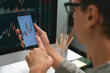 Akıllı borsa yatırımcıları ekranda akıllı telefon ile piyasa borsasını işaret ederek dizüstü bilgisayarın yanı sıra en yüksek dinamik yatırım oranını göstererek, modern işyerindeki veri planlamasına odaklanıyorlar. Bireysel.