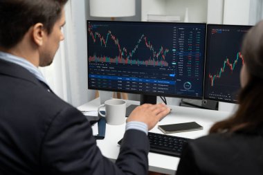 Dinamik borsada döviz kuru yatırımını tartışan iki ticaret simsarı iki bilgisayar ekranında gerçek zamanlı risk grafiği ya da modern ofisteki kar noktasını karşılaştırıyor. Varsayım.