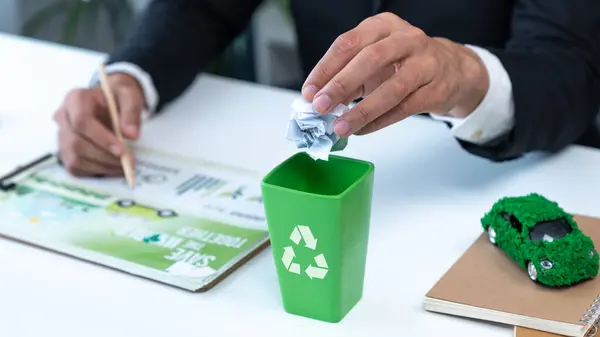 stock image Businessman put paper waste on small tiny recycle bin in his office symbolize corporate effort on eco-friendly waste management by recycling for greener environment and zero pollution. Gyre