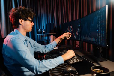 Genç yatırımcı hisse senedi tüccarı internetteki mevcut pazar grafiğinin çekici dinamik döviz kuru ekranlarıyla karşılaştırarak modern ofisteki finans grafik monitörünü işaret ediyor. Toplayıcı.