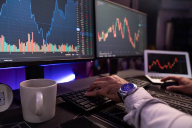 Akıllı tüccar işadamlarının elleri dinamik borsa yatırımlarına yoğunlaşarak bilgisayar ve dizüstü bilgisayara odaklanarak karanlıkta neon ışıklı ofisteki arama pazarında yüksek kar elde ettiklerini gösteriyor. Tahmin et..