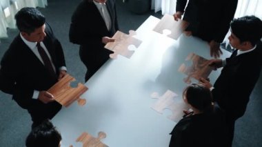 İş adamlarının toplantı odasında yapboz yapmaları. Profesyonel pazarlama ekibi yapboz parçalarını toplarken masada duruyor. Birlik, işbirliği ve ekip çalışmasını göster. Müdürlük.