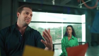 Profesyonel iş adamları yaratıcı pazarlama fikrini modern ofiste tartışırlar. İş adamları cam tahtada yapışkan notlar kullanarak finansal plan üzerinde çalışıyor. Yönlendirici.