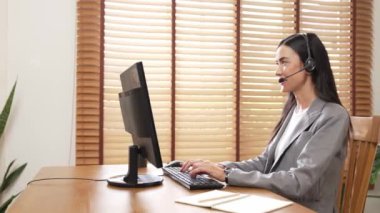 Kadın çağrı merkezi operatörü ya da müşteri hizmetleri çalışanı, müşteriye yardım etmek için kulaklıkla konuşurken çalışma alanı üzerinde çalışıyor. Profesyonel modern iş hizmeti. Blithe