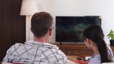 Grandfather and granddaughter eat french fries watch interesting entertainment on TV. Senior use technology communicate with young generation cross generation gap strengthen family bond. Divergence.