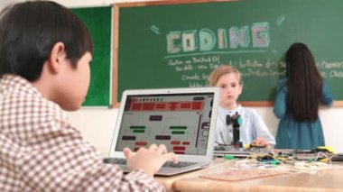 Kafkas arkadaşı STEM sınıfında elektrik panosunu tamir ederken Asyalı çocuk kodlama programı. Enerjik öğrenci kodlama mühendisliği komut yazarken ve yapay zeka yazılımını programlarken tahtada duruyor. Pedagoji.