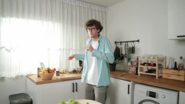 Mutlu baba yemek pişirirken müziğe geçiyor ve modern mutfakta öğle yemeği hazırlıyor. Aktif baba, sebze ve mutfak gereçleri ile çevrili sağlıklı yemek ya da salata yaparken şarkıyla dans ediyor. Pedagoji.
