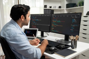 Akıllı IT geliştiricisi laptop ve iki pc ekranda kodlanan kağıtlar üzerine veri notları yazarak modern ofiste uygulama programı güncelleme sürüm sistemi yaratıyor. Tahmin et..