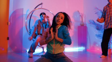 Çekici mutlu dansçı kameraya bakarken zeki kadın neon ışıkla kafiyeli hareket ediyor. Profesyonel İspanyol şarkıcı çeşitli arkadaşlarıyla renkli kıyafetler giyerken break dans yapıyor. Mutluluk.