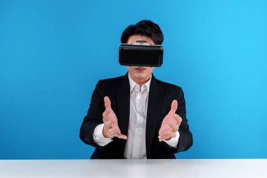Asyalı işadamı VR 'ı kullanarak veri nesnesini havada tutuyor iş dünyasının fütüristik yenilikçi teknolojisini analiz ediyor izole edilmiş mavi telif uzayındaki sanal gerçekliği inceliyor. Entrika.