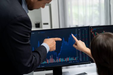Dinamik borsada döviz kuru yatırımını tartışan iki ticaret simsarı iki bilgisayar ekranında gerçek zamanlı risk grafiği ya da modern ofisteki kar noktasını karşılaştırıyor. Varsayım.