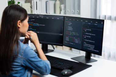 Genç Asyalı bilişim geliştiricisi güzel poz için online bilgi topluyor. Kodlama programı verileriyle birlikte kotlu tişört giyiyor. Güvenlik analizi ile çevrili iki ekran. Taktik.