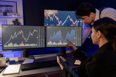 Dinamik döviz kuru risk yatırımı üzerine tartışan iki tüccar tablet üzerindeki verileri karşılaştırarak, gece neon ışıklı ofis odasındaki bilgisayar ekranlarının arka planına işaret ediyorlar. Varsayım.