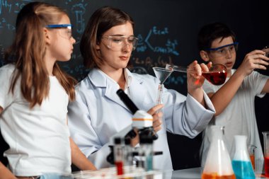 Laboratuvarda çalışan öğretmen, güvenlik gözlüğü takıyor, STEM sınıfında kimya bilimi üzerine deney yapıyor. Öğrenci komedisi tüpte sıvı deneyi yapar. Etkinlik.