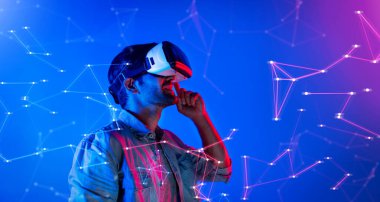 Zeki beyaz adam neon ışıkta dururken VR gözlük takıyor. Teknoloji yeniliklerini kullanarak görsel gerçeklik gözlüğünü kullanarak metaevren ya da görsel dünya programını bağlayabiliyor. Sapma.