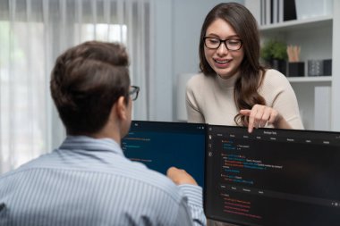 Masada çalışan erkek programcının karşısında duran kadın meslektaşım iki bilgisayar ekranında kodlama web sitesi yazılım sistemi projesini tartışmak için tam yığın veri dizaynı ile karşılaştırıyor. Varsayım.