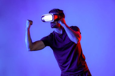 VR gözlük takan, kameraya vuran ya da yumruklayan zeki bir adamın yan görüntüsü. Dijital teknoloji yeniliklerini kullanırken sporcu boks ve metaevren veya sanal dünyada hareketli jest. Sapma.