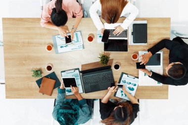 Modern ofisteki iş adamları ve iş kadınlarıyla grup toplantısındaki iş adamlarının en üst düzey görüşü, masada dizüstü bilgisayar, kahve ve belge ile. Kurumsal şirketler uds