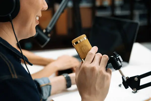 stock image Selective focusing of smart radio influencer host wearing jeans with mic on channel social media online live streaming on blurry background with woman coworker at morning at studio record. Infobahn.