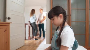 Stresli ve mutsuz genç kız köşeye kıvrılıp kulaklarını kapatarak arka planda ebeveyninin tartışmasını engelliyor. Evde aile içi şiddet ve travmatik çocukluk depresyona dönüşür. Titiz