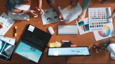 Takım ayakta dikilirken ve yorum yaparken müdürün fikir yazma konusunda üst düzey görüşü. Profesyonel tasarımcı logosu renk paletine bakarken ve renkli kalemle fikri kağıda yazarken. Sempozyum.