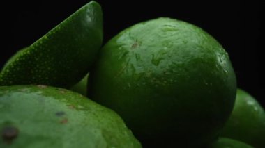 Limon dilimleri titizlikle bir yığın halinde, siyah arkaplana göre dizilmiş. Her bir kireç dilimi çarpıcı detaylar, canlı yeşil rengi ve baştan çıkarıcı dokusu ile yakalanır. Kapatın. Geliştirilebilir.