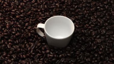Kahve fincanının içine kahve çekirdeği yığını ile çevrili bir şekilde düşüyor. Beyaz fincana aromatik fasulye döküyorum. Kahvenin üst görüntüsü siyah arka planlı cama düşer. Geliştirilebilir.