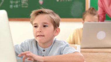 Çeşitli çocuklar yazılım sistemini programlarken beyaz çocuk dizüstü bilgisayarda çalışıyor. Öğretmen ve öğrenci sorunları çözmek ve kodlama mühendisliğini desteklemek için erkek bilgisayar ekranına bakıyor. Pedagoji.