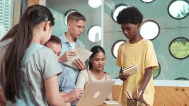 Akıllı robotlar sınıfta dizüstü bilgisayar ekranını işaret ederken, beyaz bir öğretmen yorum yapıyor ya da öğrencilere tavsiye veriyor. Öğretmen bilgisayar kullanırken çeşitli öğrencilerin ders verirken not alması. Öğretim