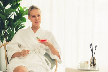 Güzellik ya da vücut bakımı güzellik salonu yaşam tarzı konsepti. Bornoz giyen bir kadın lüks otel kaplıcalarında ya da tatil odasında içkiyle rahatlıyor. Tatil ve boş zaman rahatlığı. Sessiz.