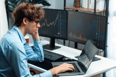 Monitörlerdeki gerçek zamanlı dizüstü bilgisayarda pazar stoğu grafik veri yatırımına odaklanan genç bir tüccar üzerinde çalışıyor. Modern ofiste. Dinamik para bozdurma oranını analiz etme kavramı. Toplayıcı.
