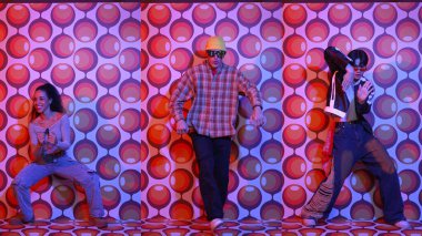 Parti sahnesinde kameraya bakarken balon geçmişiyle birlikte dans eden mutlu çok kültürlü dansçılar. Zeki hipster grubu müzik yapıyor ve sokak dansı yapıyor. Tam vücut. Mutluluk.