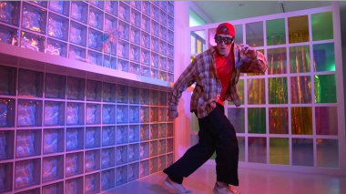 Komik break dansçı kameraya bakarken hiphop 'a doğru serbest adım atıyor. Çılgın mutlu hipster dans edip sokak dansı yaparken Led ışığında günlük kıyafet ve güneş gözlüğü takıyor. Mutluluk.