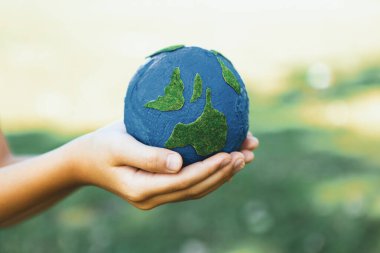 Dünya gezegenini ESG ilkesi ve çevre dostu enerjisiyle daha parlak bir gelecek için Dünya günü olarak el ele tutuşan genç çocuklar. Döngü