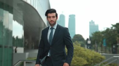 Şehirde ya da parkta duran profesyonel iş adamı. Gülümseyen proje yöneticisi kameraya bakarken kendine güvenen kollarla gülümsüyor. Mimari binasında takım elbise giyen yatırımcılara yakın çekim. Sevinçli..