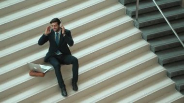 Merdivenlerde otururken kulaklıktan müzik dinleyen zeki bir iş adamı. Mutlu menajer dans ederken ya da müzikle uğraşırken gülümsüyor. Yatırımcı iyi haberler alıyor, terfi alıyor. Sevinçli..