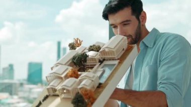 Yetenekli genç beyaz mimarın sol ve sağ taraftaki asansör evi modelini yakından incele ve hata noktasını gökdelen ile kontrol etmeye odaklan. İzleme