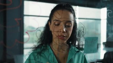 Zeki, profesyonel İspanyol iş kadınının portresi renkli yapışkan notlarla cam tahtaya pazarlama fikirleri yazıyor. Genç yönetici, analiz iş planının zihin haritasını çiziyor. - Yakın çekim. Yönlendirici.