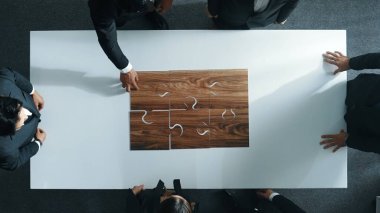 İş adamlarının toplantı odasında yapboz yapmaları. Profesyonel pazarlama ekibi yapboz parçalarını toplarken masada duruyor. Birlik, işbirliği ve ekip çalışmasını göster. Müdürlük.