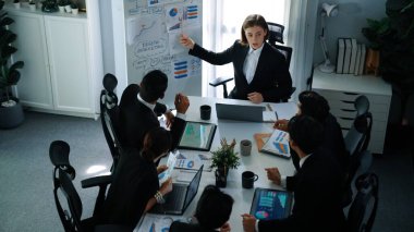 Akıllı yönetici projesinin üst görünümü beyaz tahtaya zihin haritası ve finansal grafik ile işaret ediyor ve çeşitli yatırımcılar hisse yatırım grafiğini dinleyip analiz ederken pazarlama fikrini açıklıyor. Müdürlük.