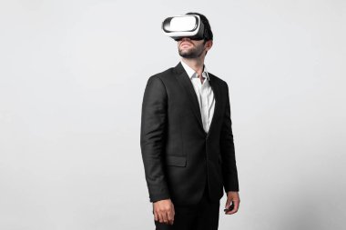 VR gözlüklü yetenekli bir proje yöneticisi ayakta dikilip etrafa bakıyor. Beyaz iş adamı takım elbise giyerken metaevren ve sanal gerçeklik dünyasına bağlanıyor. Yenilik teknolojisi. Sapma.